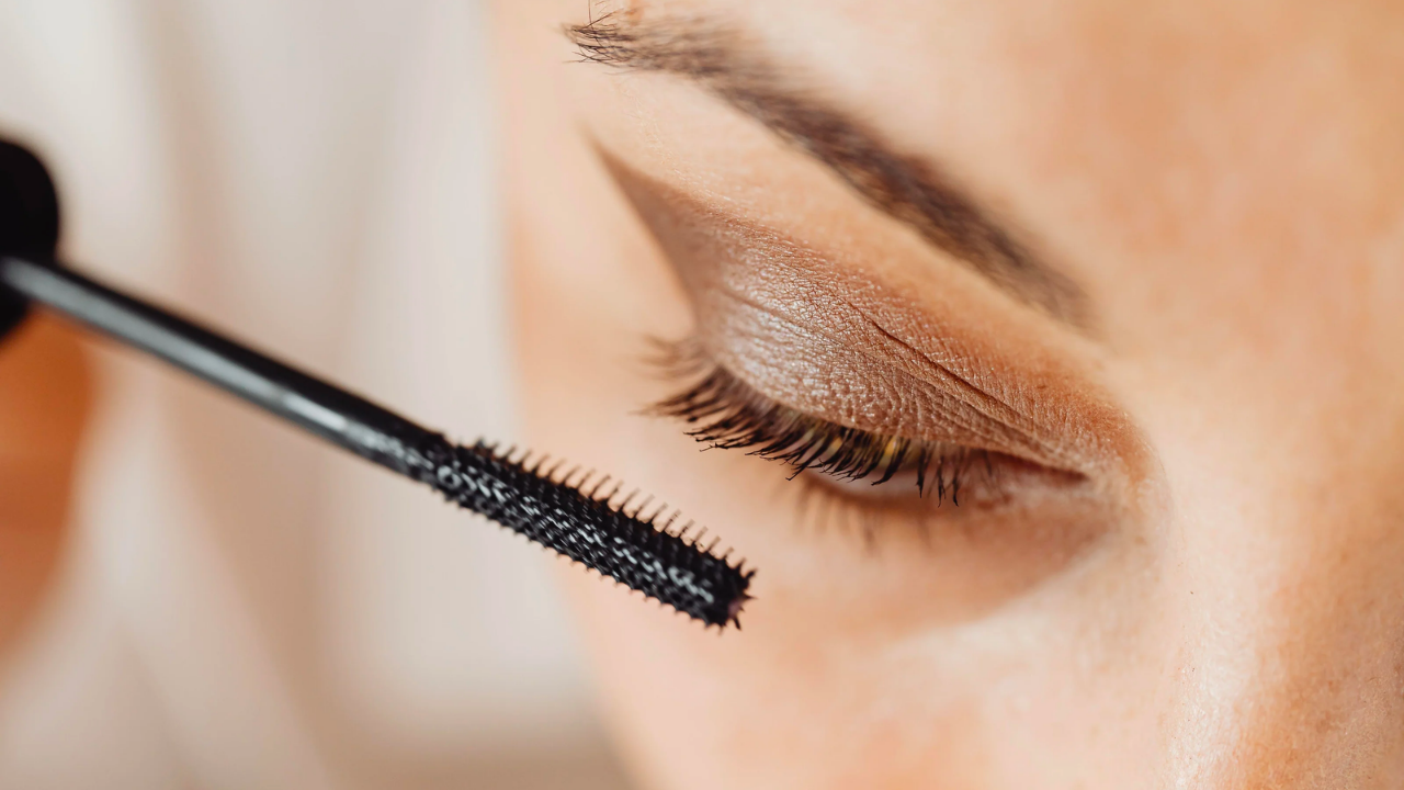 A woman applying mascara to her lashes